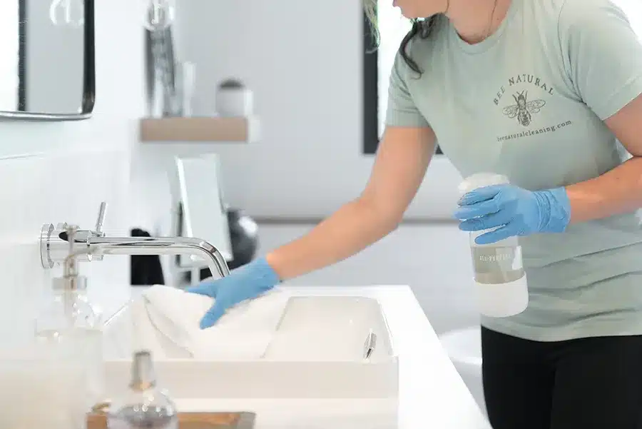 Bee Natural Cleaning Services image of lady cleaning bathroom sink - Bee Natural Residential and Commercial Cleaning Service in Georgetown, Texas